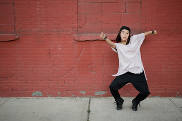 Young Asian woman dancing hip hop in city