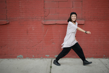 Young Asian woman dancing hip hop in city