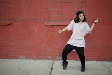 Young Asian woman dancing hip hop in city