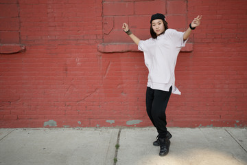 Young Asian woman dancing hip hop in city