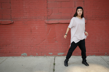 Young Asian woman dancing hip hop in city