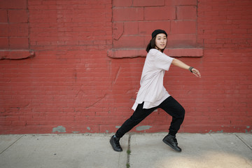 Young Asian woman dancing hip hop in city