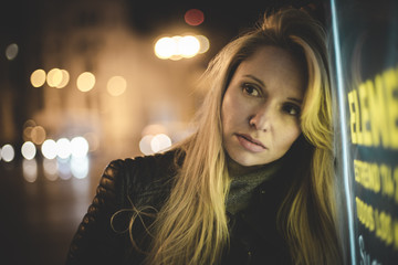 sensual blond in the city at night, with neon lights and a sign