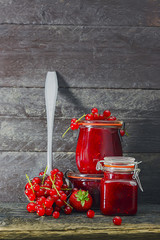  Marmelade im Glas mit frischen Beeren,  rustikaler Hintergrund