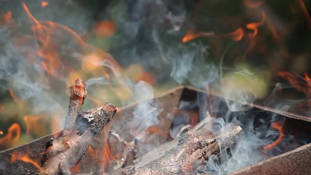branches of cherry wood stacked in a barbecue burning bright red flames