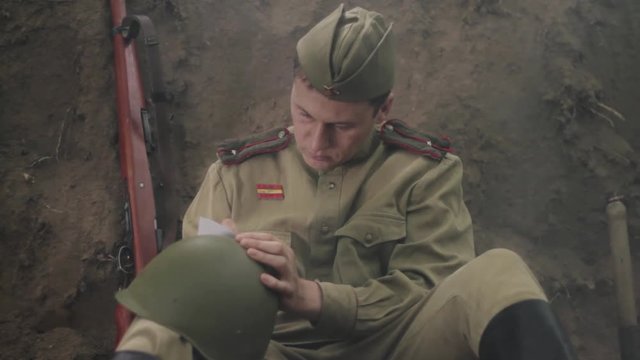 Soviet soldier sits in the trenches, and writes a letter. World War II.