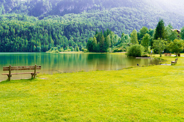 bench in green park and lake in alps