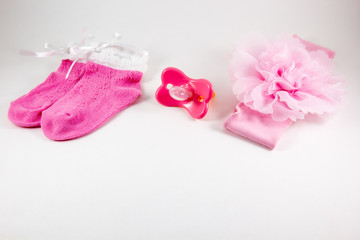 Baby socks, pacifiers and bow on a white background