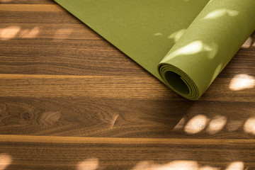 Yoga mat on a wooden background. Equipment for yoga. Concept healthy lifestyle. Lots of copyspace - obrazy, fototapety, plakaty