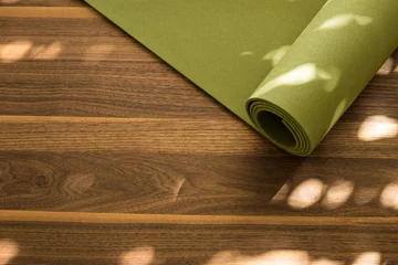 Yoga mat on a wooden background. Equipment for yoga. Concept healthy lifestyle. Lots of copyspace © nataliafrei