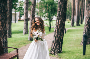 Obraz na płótnie Canvas beautiful bride with white bouquet in park
