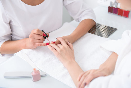 Skillful beautician doing manicure for girl