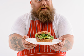 Happy male chef presenting burger