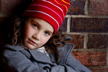 Portrait of a beautiful young girl leaning on brick wall