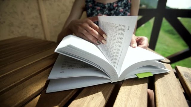 Woman flips a page while reading a book. Close-up