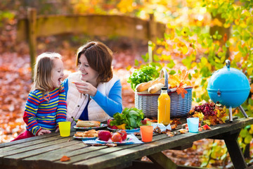 Mother and daughter set table for picnic in autumn