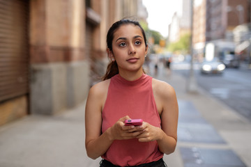 Young woman in city texting cell phone