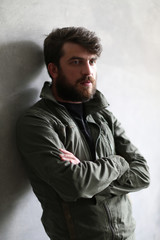 Man in khaki jacket leaning on wall with crossed hands. Close.up. Black