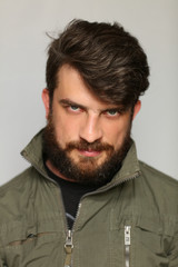 Man dressed in khaki jacket with interesting look. Close.up. Gray