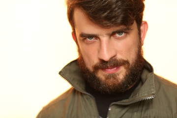 Obraz premium Bearded man wearing khaki jacket with interesting look. Close.up. White