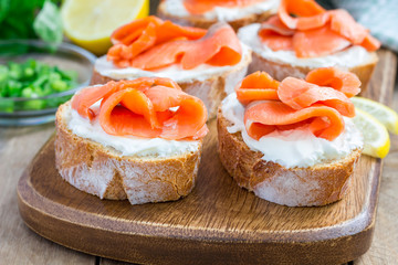 Sandwich with smoked salmon and cream cheese, wooden board, horizontal