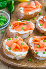 Sandwich with smoked salmon and cream cheese, wooden board, vertical