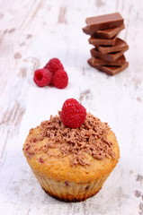 Fresh baked muffins with raspberries and chocolate on wooden background, delicious dessert