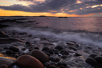 oulder  beach with blurred motion sea wave before sunrise