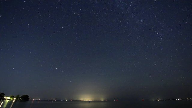 Night sky with stars and the Milky Way circling around Polaris, the North Star over lake, fireballs from the annual Perseid Meteor Shower falling off with bright light streaks.