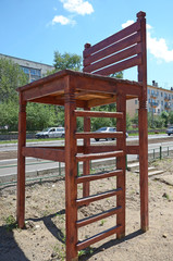 Fototapeta na wymiar Big wooden chair in the yard of living house in the city of Chita