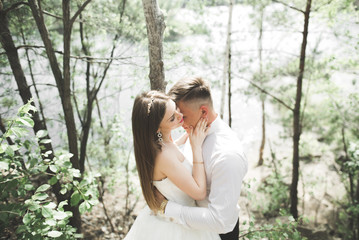 Fototapeta premium Wedding couple man, bride kissing and hugging on a background of the river, mountains. Beauty portrait