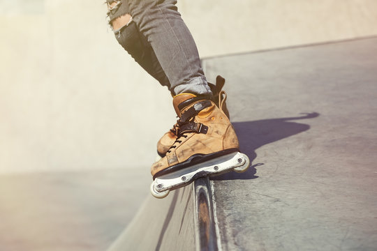 Aggressive inline rollerblader grinding on ramp in skatepark