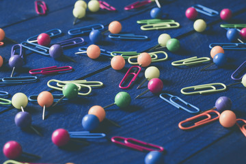 background of scattered colored round pins and paper clips on a table