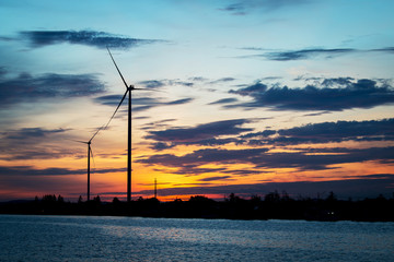 Silhouette of wind turbine at river background