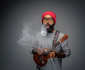 Male holding acoustic small guitar and smoking a cigarette.