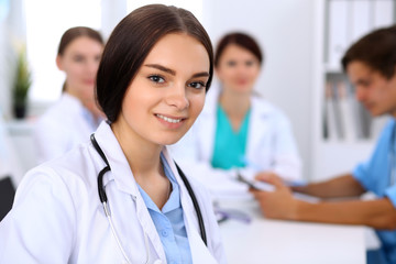 Fototapeta premium Happy doctor woman with medical staff at the hospital sitting at the table and discussing medical history