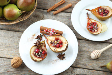Fototapeta na wymiar Baked pears with honey, walnuts and cranberries on grey wooden t