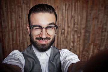 Funny stylish young guy doing selfie on a wooden background