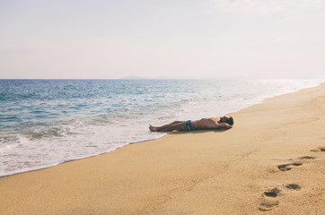 Fototapeta na wymiar Young man lying on a sandy beach 