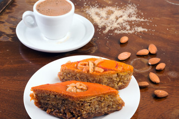 Baklava, cup of black coffee and almonds on table in café or ol