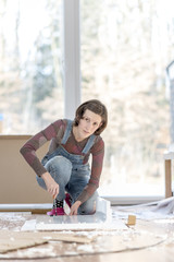 Woman in overalls working on floor in home