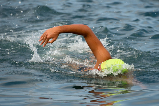 Swimmer floating crawl into the blue sea.
