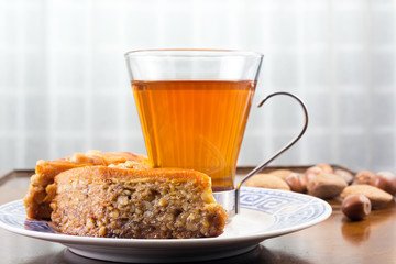 Baklava, glass of tea and nuts on cafe table or old coffee table