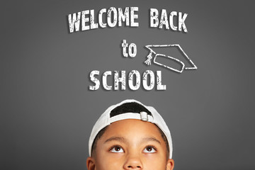 Cute afro american teenager and text welcom back to school on gray background. School concept.