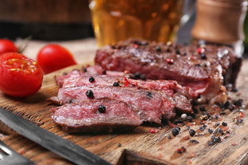 Tasty grilled steak with beer on cutting board