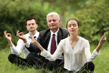 Business people relaxing in meditation pose in park