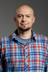 Fototapeta premium Portrait of cheerful handsome middle-aged man in plaid shirt looking at camera smiling over grey background.