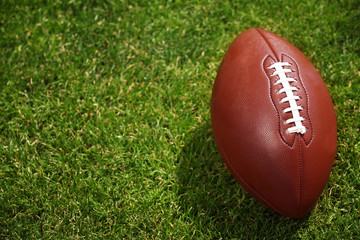 American football ball on a green grass
