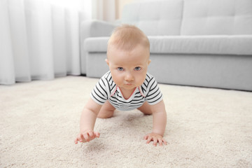 Adorable little baby crawling on light carpet