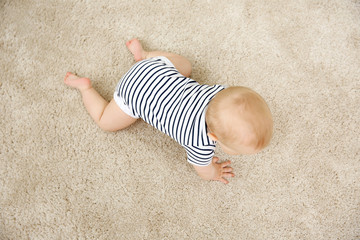 Adorable little baby crawling on light carpet